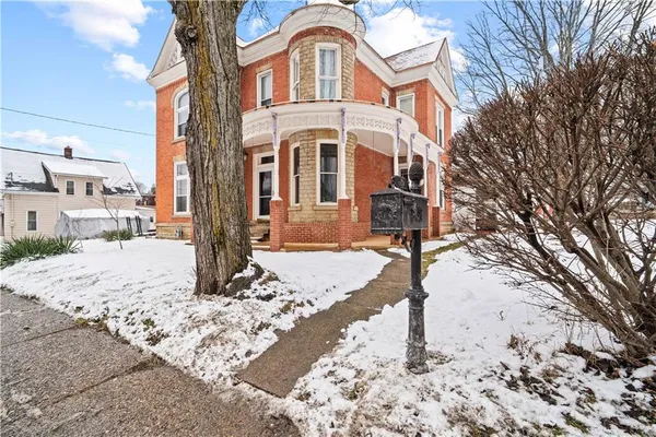 a front view of a house with a yard covered in snow