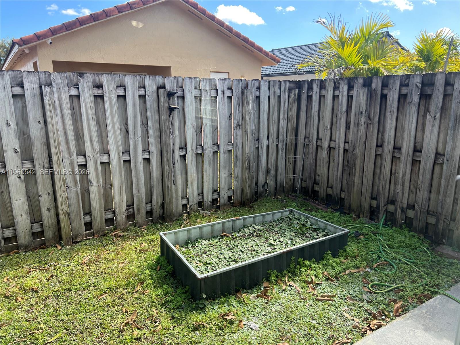 14225 Southwest 149th Avenue, Unit 14225 Miami, FL 33196 - Photo 18 of 19 a view of a wooden fence with a small yard