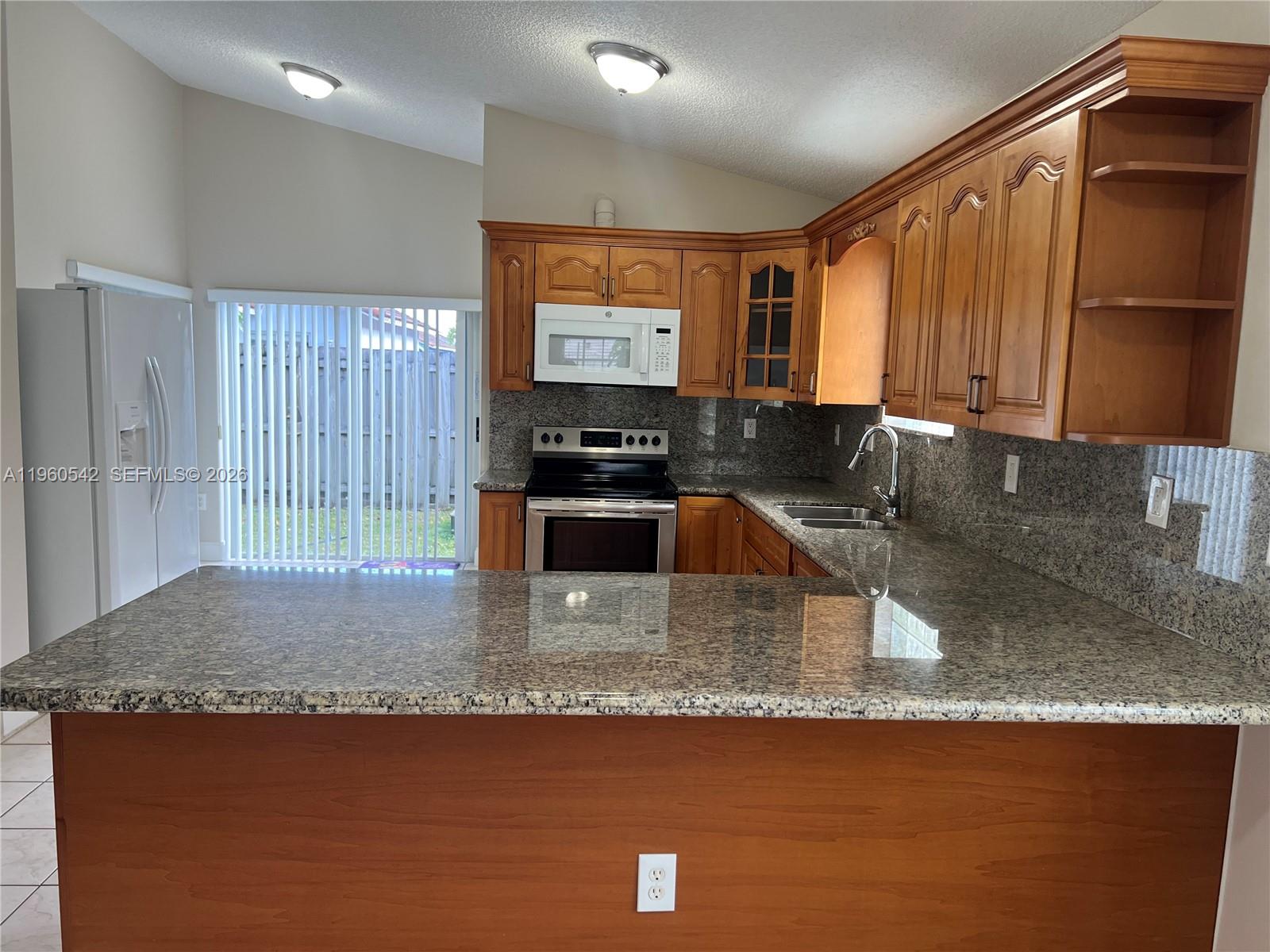 14225 Southwest 149th Avenue, Unit 14225 Miami, FL 33196 - Photo 3 of 19 a kitchen with kitchen island granite countertop a sink a counter top space and cabinets