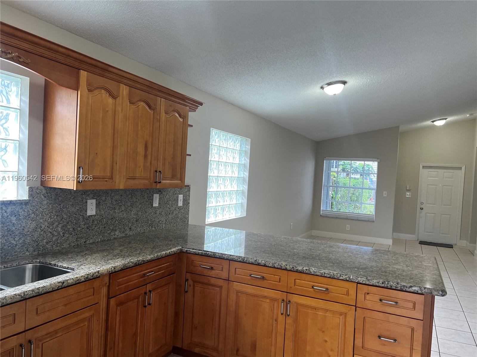 14225 Southwest 149th Avenue, Unit 14225 Miami, FL 33196 - Photo 4 of 19 a kitchen with granite countertop white cabinets sink and window