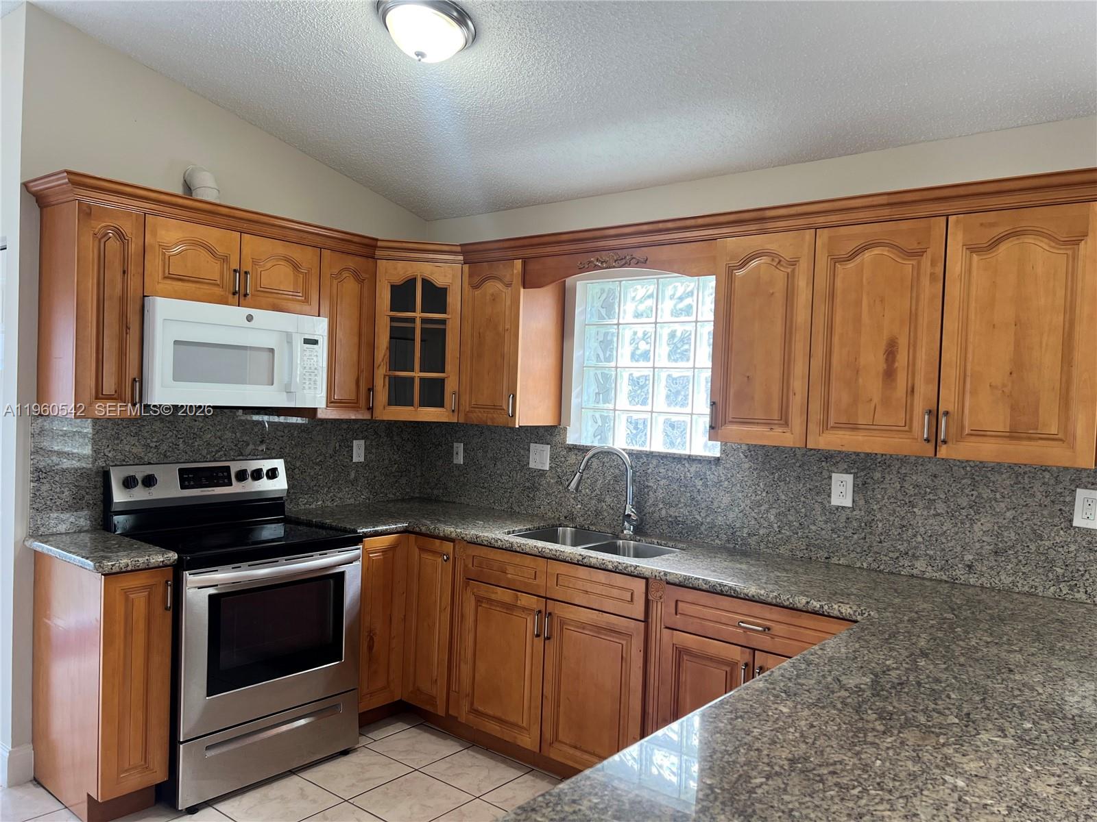14225 Southwest 149th Avenue, Unit 14225 Miami, FL 33196 - Photo 5 of 19 a kitchen with stainless steel appliances granite countertop a sink stove and cabinets