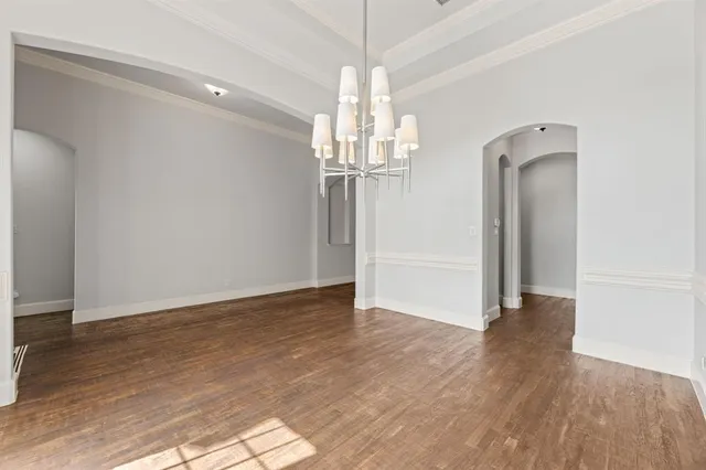a view of a hallway with wooden floor and chandelier