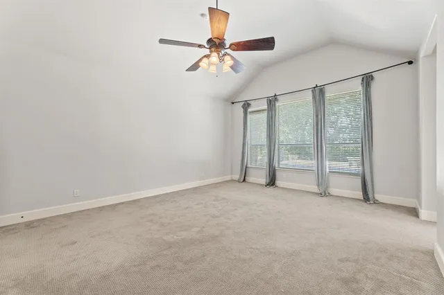 an empty room with chandelier fan and windows
