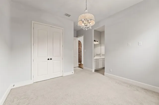 an empty room with a chandelier fan and wooden floor