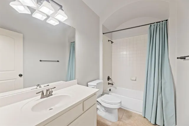 a bathroom with a toilet a sink a mirror a shower a vanity and window