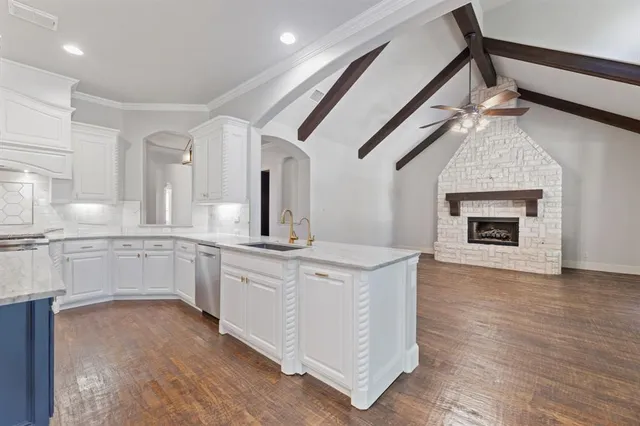 a open kitchen with stainless steel appliances granite countertop a stove top oven a sink and dishwasher with wooden floor