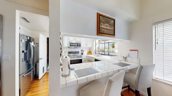 a kitchen with stainless steel appliances white cabinets sink and wooden floor