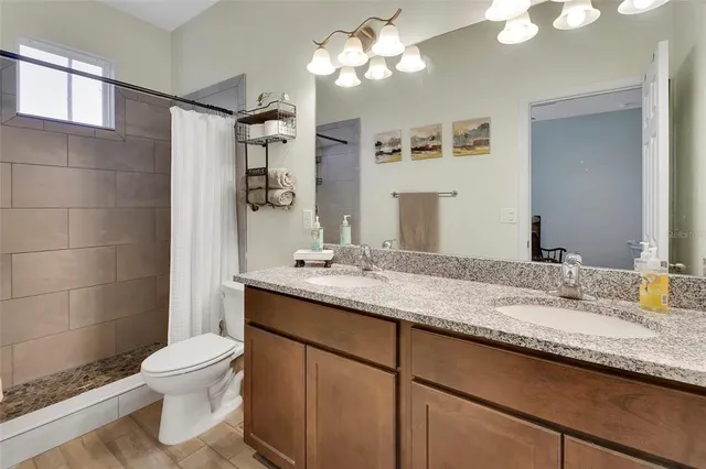 a bathroom with a granite countertop sink toilet a large mirror and shower