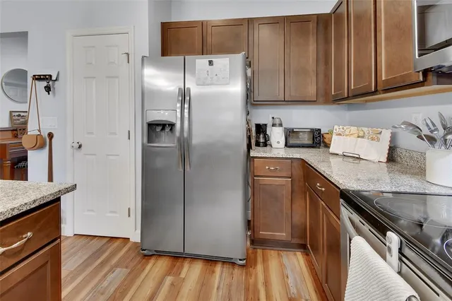 a kitchen with granite countertop a refrigerator and wooden floor