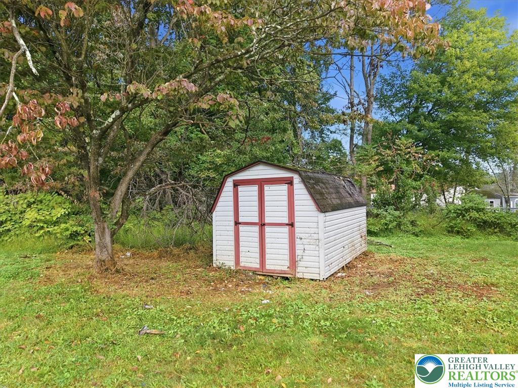 74 Swiss View Road Lehighton, PA 18235 - Photo 57 of 59 Mature trees shade a practical storage shed on a grassy yard.
