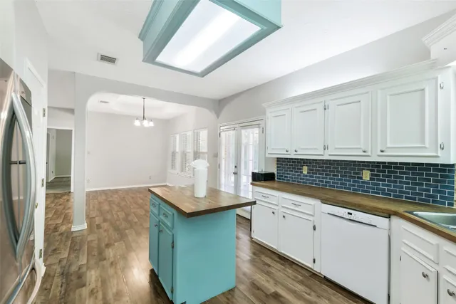 a kitchen with stainless steel appliances a refrigerator a sink dishwasher a stove and white cabinets with wooden floor