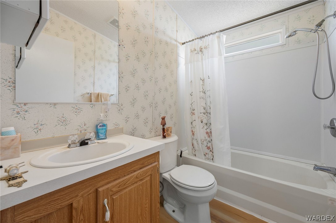 2465 Egar Road Golden Valley, AZ 86413 - Photo 36 of 98 Bathroom featuring a vanity with a white countertop and wood cabinetry, a white toilet, and a bathtub with a showerhead