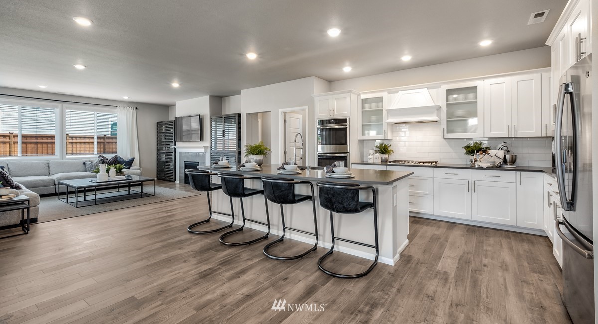 23435 41st Drive Southeast, Unit 33 Bothell, WA 98021 - Photo 7 of 24 a kitchen with stainless steel appliances kitchen island granite countertop wooden floors and white cabinets