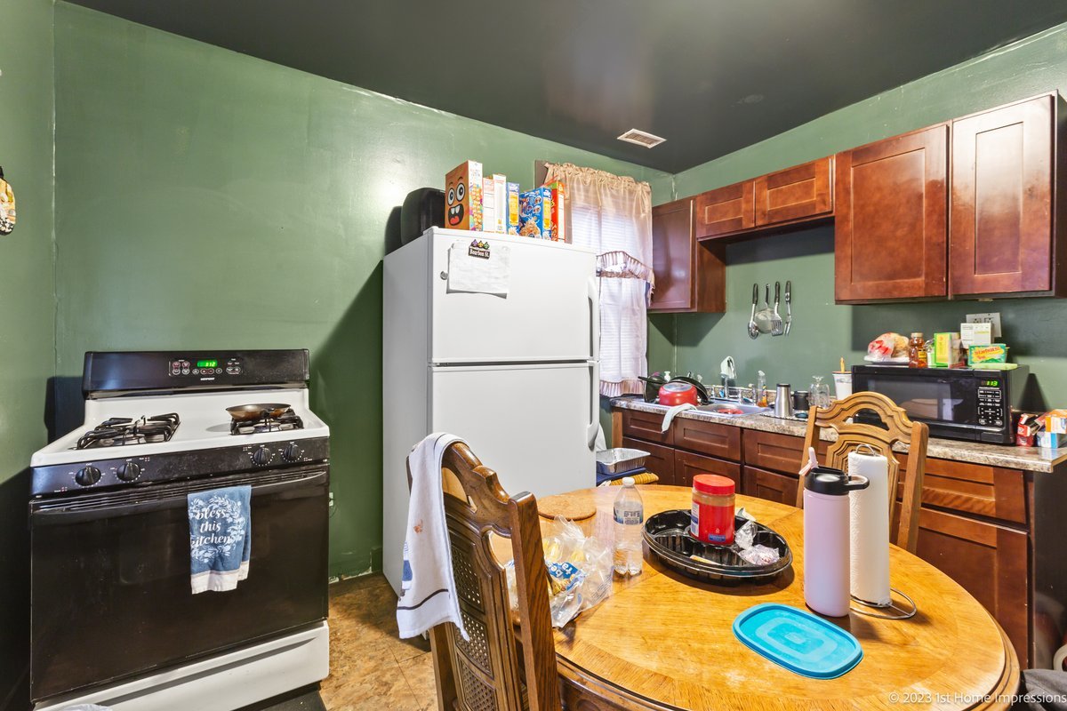 8807 South Lowe Avenue Chicago, IL 60620 - Photo 9 of 19 a kitchen with a refrigerator a stove a sink and a dining table with wooden floor