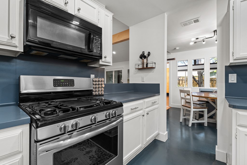 A streamlined kitchen layout boasts white cabinetry, gas range, and integrated microwave for culinary convenience.