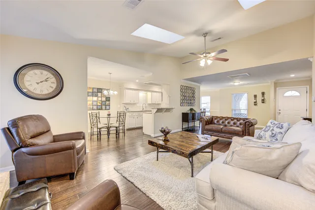 a living room with furniture a clock and a ceiling fan