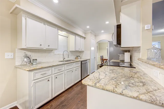 a large kitchen with kitchen island granite countertop a sink a stove counter space and cabinets