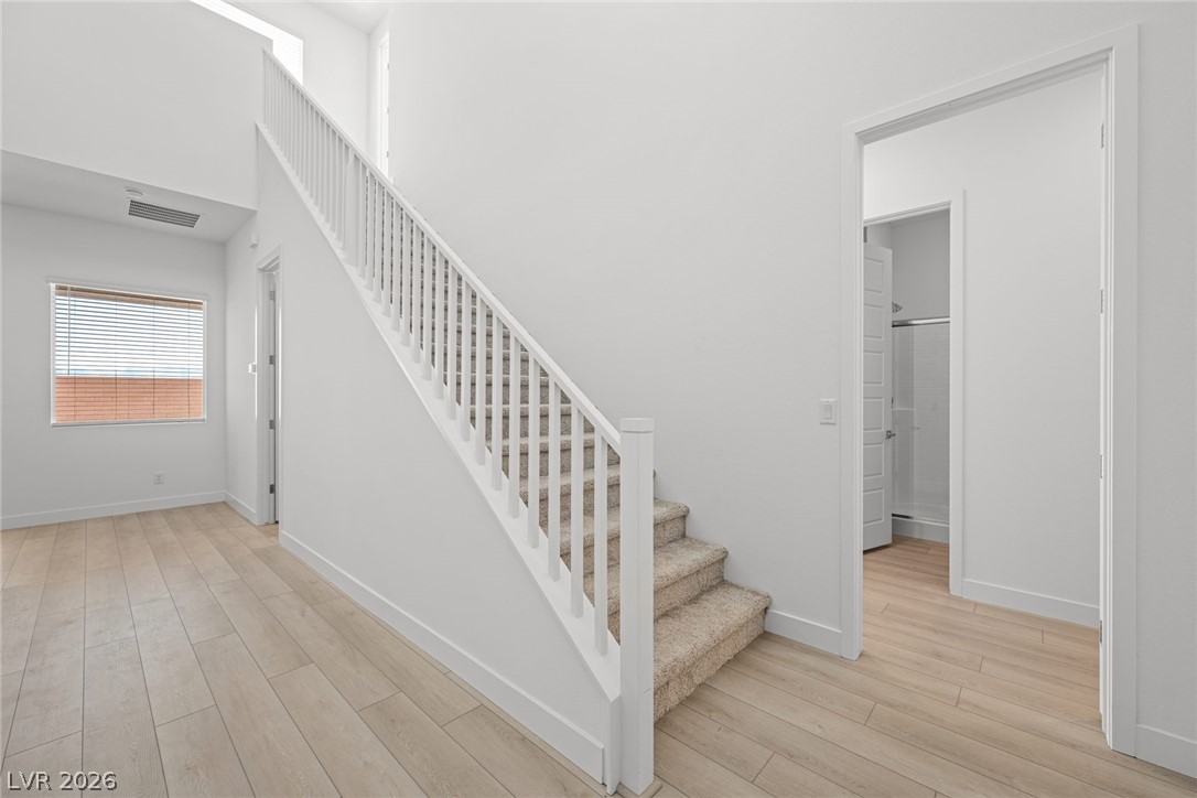 9983 Decano Ridge Street Las Vegas, NV 89141 - Photo 12 of 39 A well-lit entryway features light wood flooring and a staircase with a white railing.