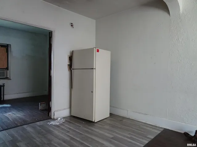 a view of a refrigerator in kitchen and an empty room