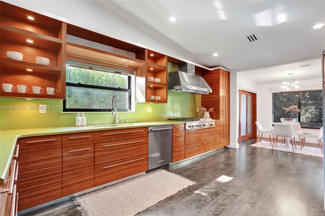 a large white kitchen with stainless steel appliances granite countertop a large stove a oven and a refrigerator with wooden floor