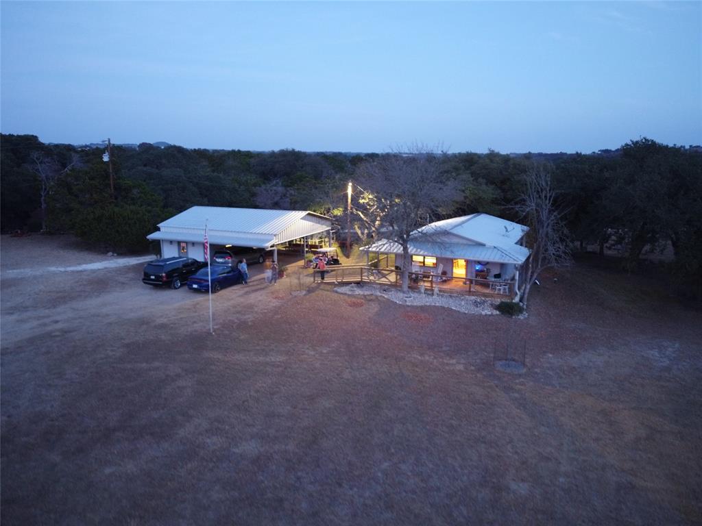 515 Big Creek Road Blanco, TX 78606 - Photo 1 of 1 The property features a primary structure with a covered porch and an additional structure providing covered parking, both with white roofs