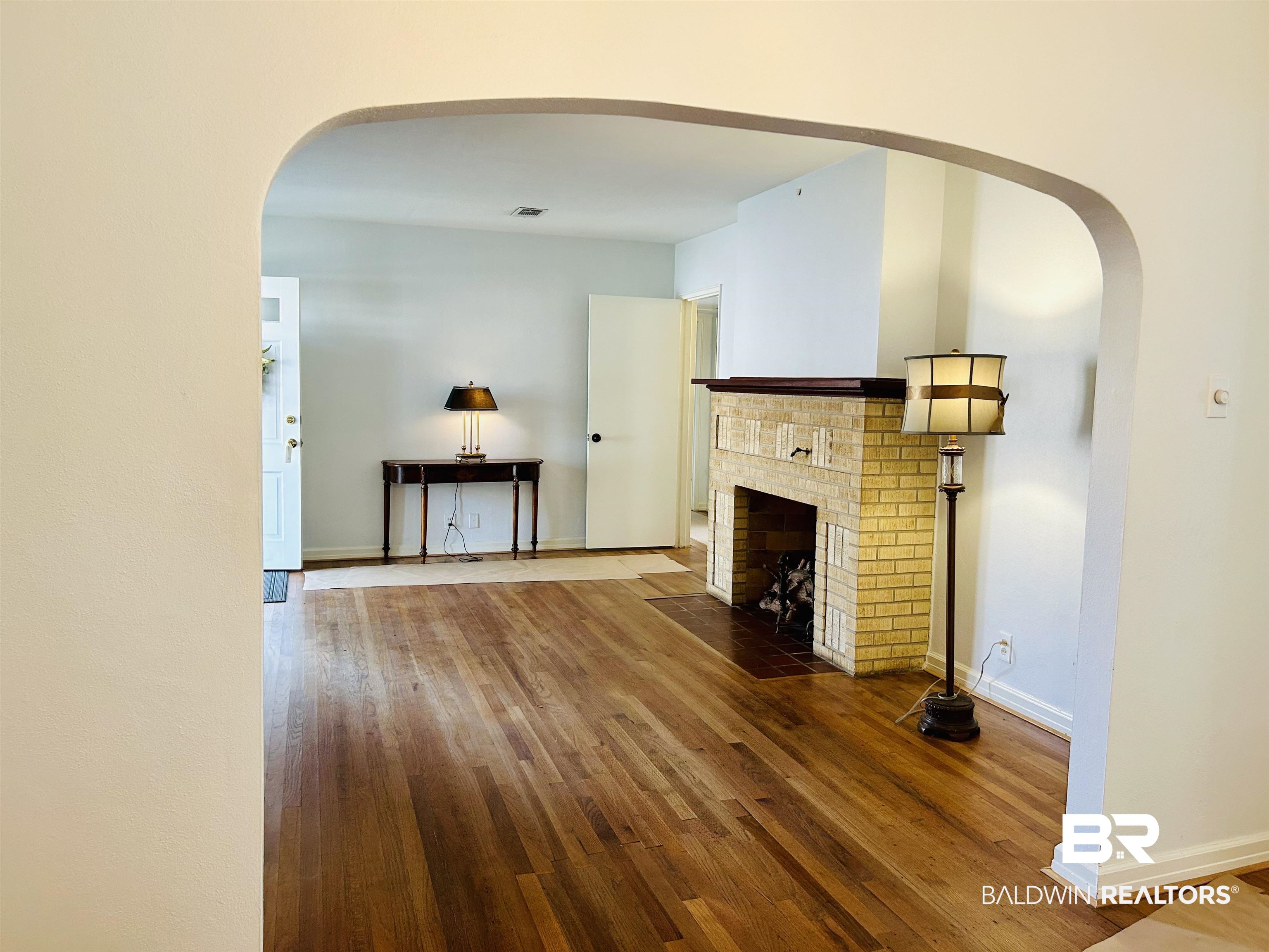 94 Diamond Street Mobile, AL 36611 - Photo 7 of 30 Unfurnished living room with wood-type flooring and a brick fireplace