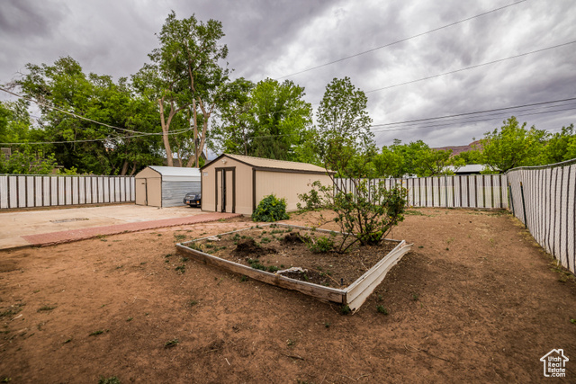 527 Palisade Drive Moab, UT 84532 - Photo 21 of 51 Fenced backyard with an outdoor structure, a storage shed, and a vegetable garden
