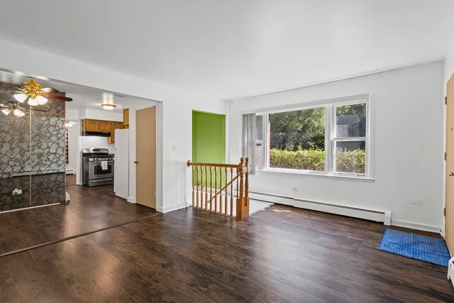 a view of an empty room with a window and wooden floor