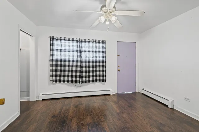 an empty room with wooden floor fan and windows