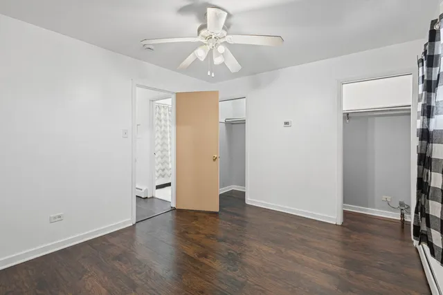 an empty room with wooden floor and a ceiling fan