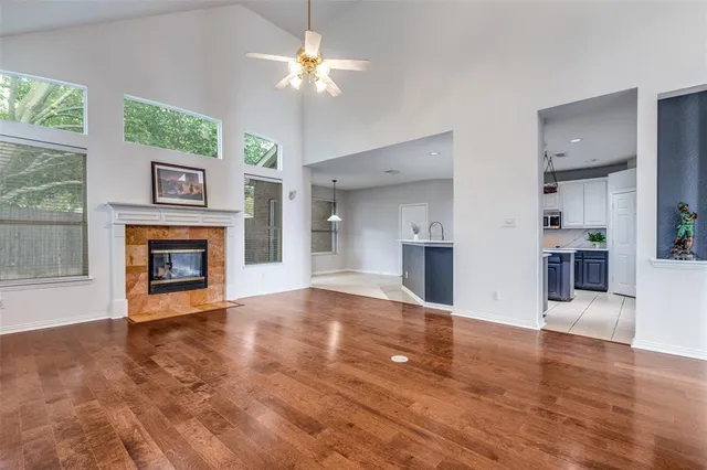 a view of a livingroom with a fireplace wooden floor chandelier and windows