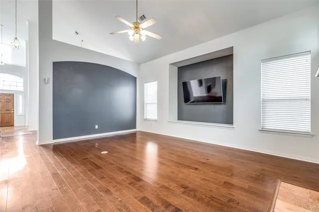 a view of an empty room with window and wooden floor