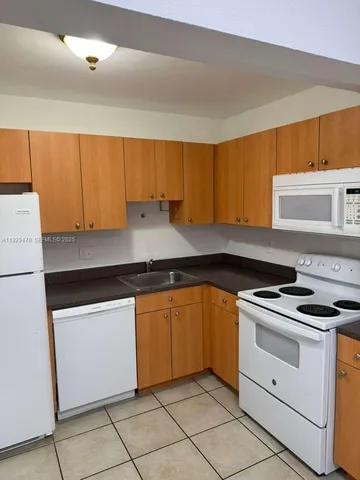 a kitchen with granite countertop cabinets sink and white appliances
