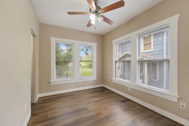 an empty room with wooden floor chandelier and windows