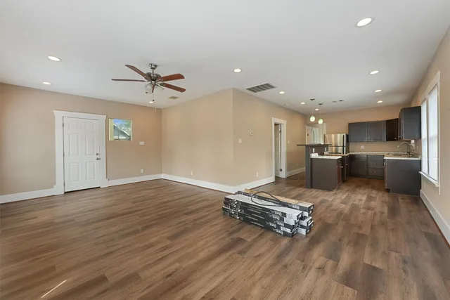 a living room with stainless steel appliances kitchen island hardwood floor and a sink