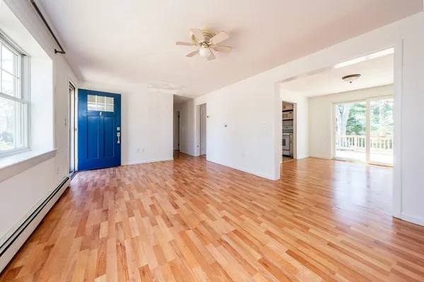 a view of an empty room with wooden floor and a window