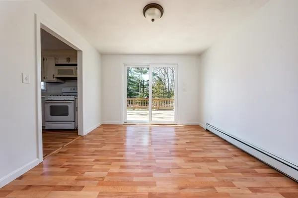 a view of an empty room with a window and wooden floor