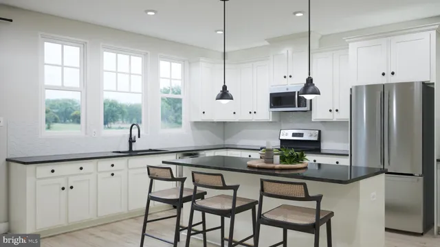 a kitchen with stainless steel appliances granite countertop a stove a sink a microwave a refrigerator and white cabinets with wooden floor