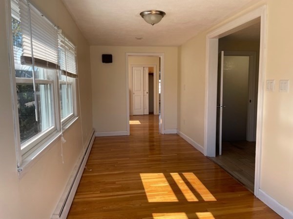 272-2 Nevada Street, Unit 2 Newton, MA 02460 - Photo 6 of 28 a view of a hallway with wooden floor and a living room