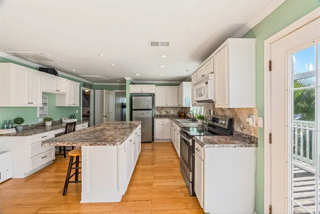 a large kitchen with kitchen island a stove a sink a refrigerator cabinets and wooden floor