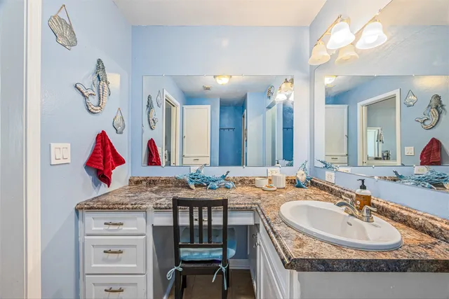 a bathroom with a granite countertop sink a mirror and a bathtub