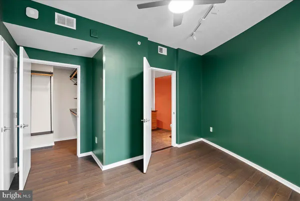 an empty room with wooden floor and a ceiling fan