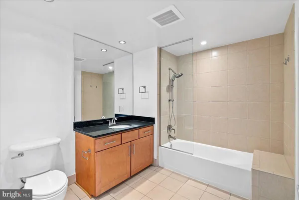 a bathroom with a granite countertop sink a toilet a mirror and bathtub