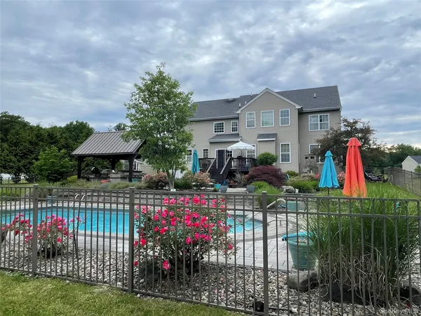 a view of a house with a flower garden and a wooden fence