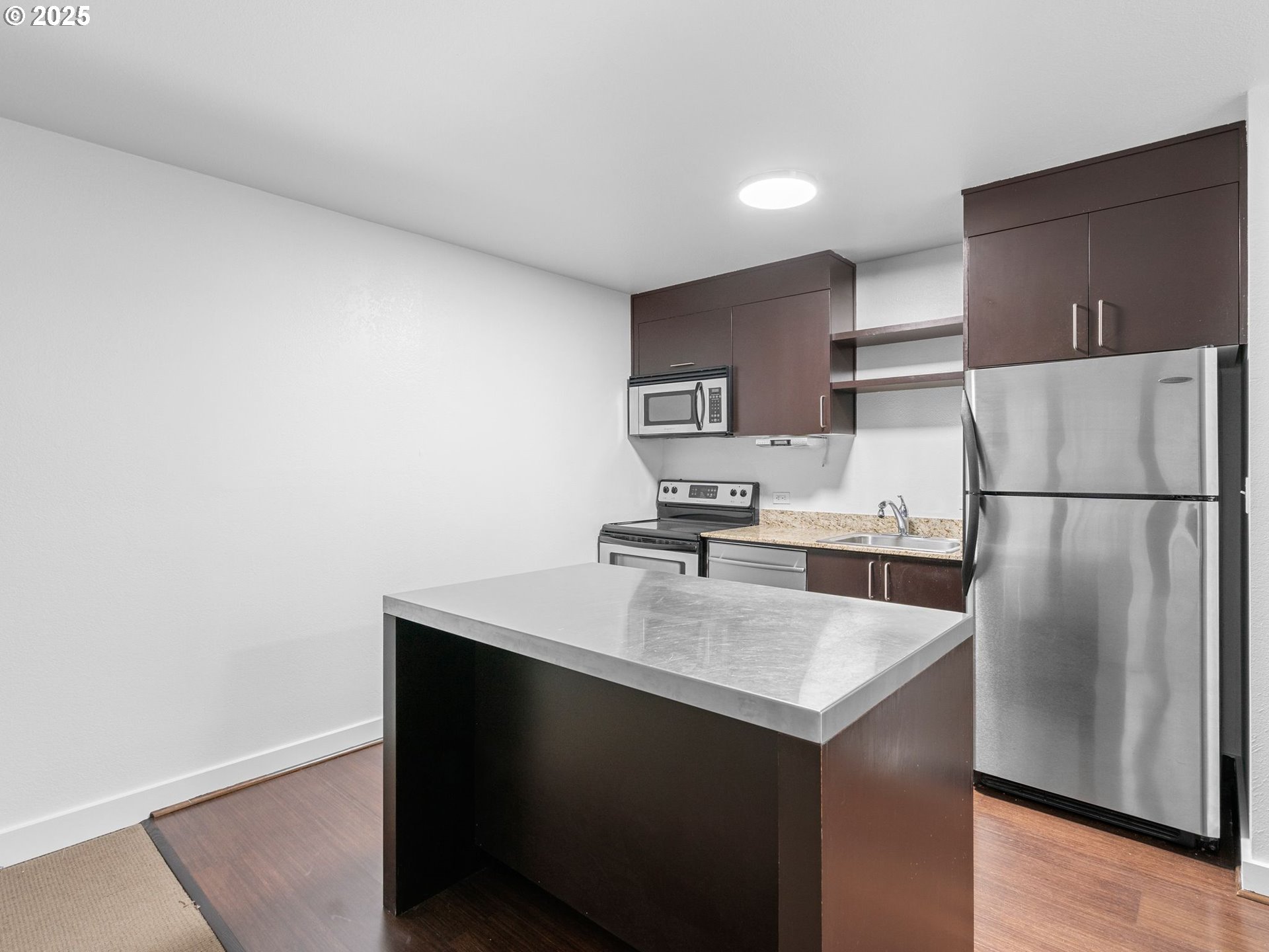 255 Southwest Harrison Street, Unit 3C Portland, OR 97201 - Photo 11 of 32 a kitchen with a refrigerator a stove a microwave and wooden floor