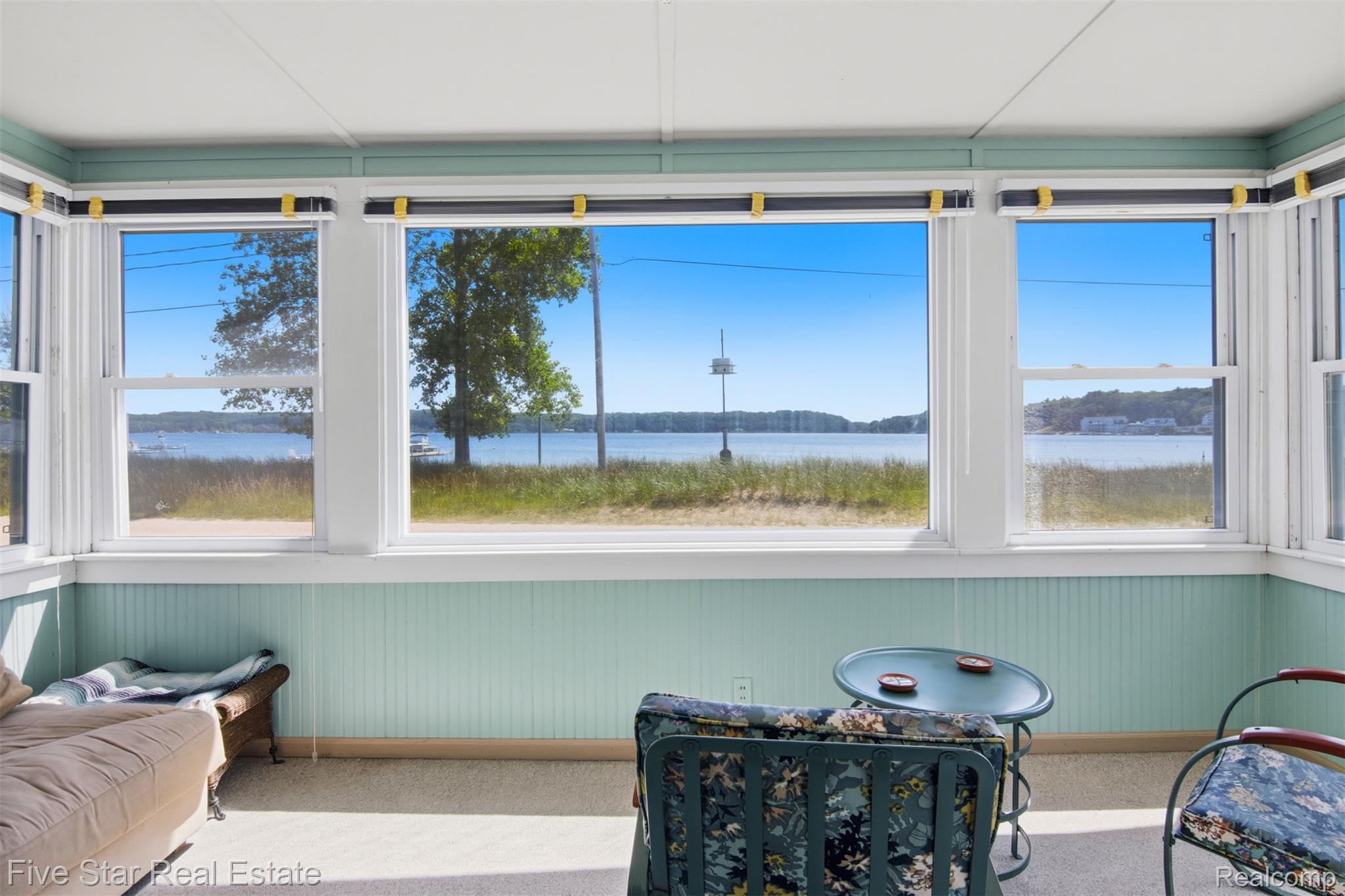 2588 Lakeview Road Onekama, MI 49675 - Photo 11 of 32 Sunporch featuring multiple large windows, water frontage, beadboard paneling, and carpet flooring