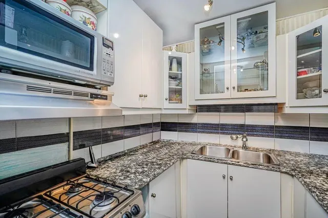 a kitchen with stainless steel appliances granite countertop a sink stove and cabinets