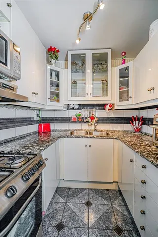 a kitchen with granite countertop a sink stove and cabinets