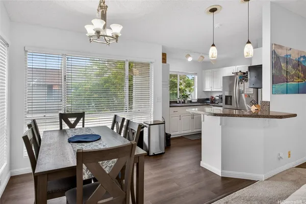 a kitchen with stainless steel appliances kitchen island granite countertop a stove a sink a refrigerator a dining table and chairs with wooden floor