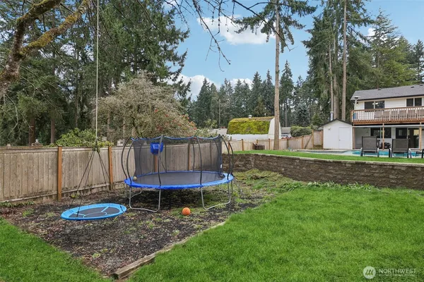 a view of a backyard with table and chairs potted plants and large tree